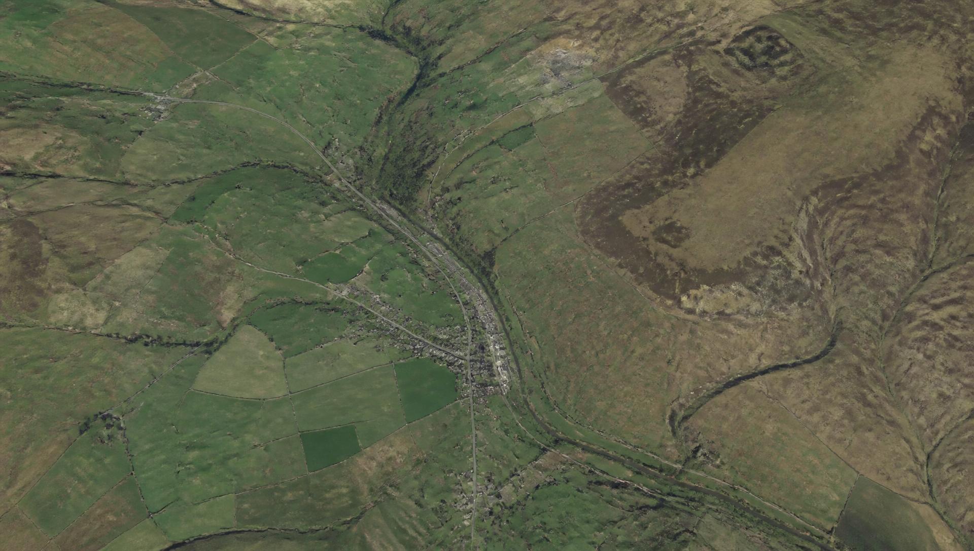 High-resolution aerial view of terrain: fields, a river valley, a settlement and fell landscape
